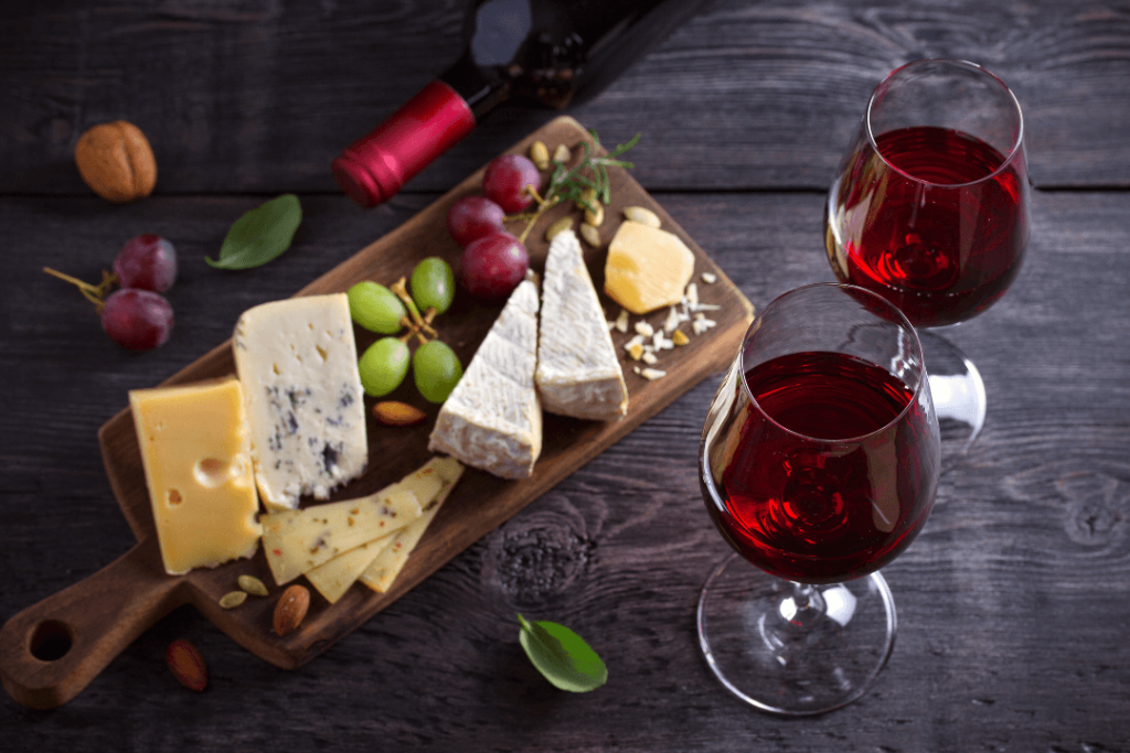 Syrový tanier a fľašou červeného vína Primitivo a dvomi naliatými pohármi červeného vína